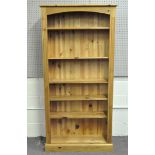 A large modern pine bookshelf, with five shelves within reeded sides,