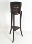 An oak jardiniere stand in the form of a barrel with metal rings on three splayed legs,