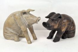 Two decorative wooden pigs, one pale, one stained dark brown,