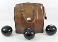 A mixed set of three lawn bowls in a vintage fitted leather carry bag