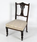 A Victorian mahogany lyre back nursing chair with carved details, on casters, with cream upholstery,