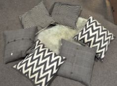 A group of cushions in black and white zigzag pattern and grey examples,