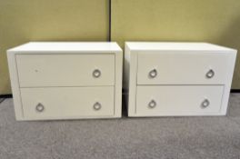 A pair of modern white bedside units, each with two drawers and chromed handles,