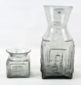 Two mid-century smoky grey Dartington glass vases of square body with raised meander pattern,