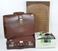 A set of four lawn bowls in a small briefcase with a further briefcase and a wooden score board