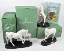 Three white Royal Doulton sculptures of horses and a Royal Doulton Winnie the Pooh bowl and mug