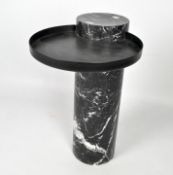 A modern coffee table modelled as a marble column with circular metal surface mounted to one side,