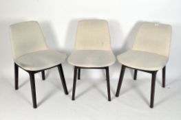 Three contemporary chairs on dark stained wood supports, upholstered in cream linen,