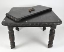 A late 19th century dark stained extendable table with carved rim, on heavy carved pedestal legs,