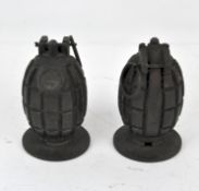 Two novelty pineapple grenade paperweights, each mounted to a circular stand,