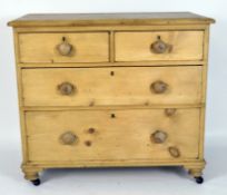 An early 20th century pine chest of four drawers with round knobs, on casters,