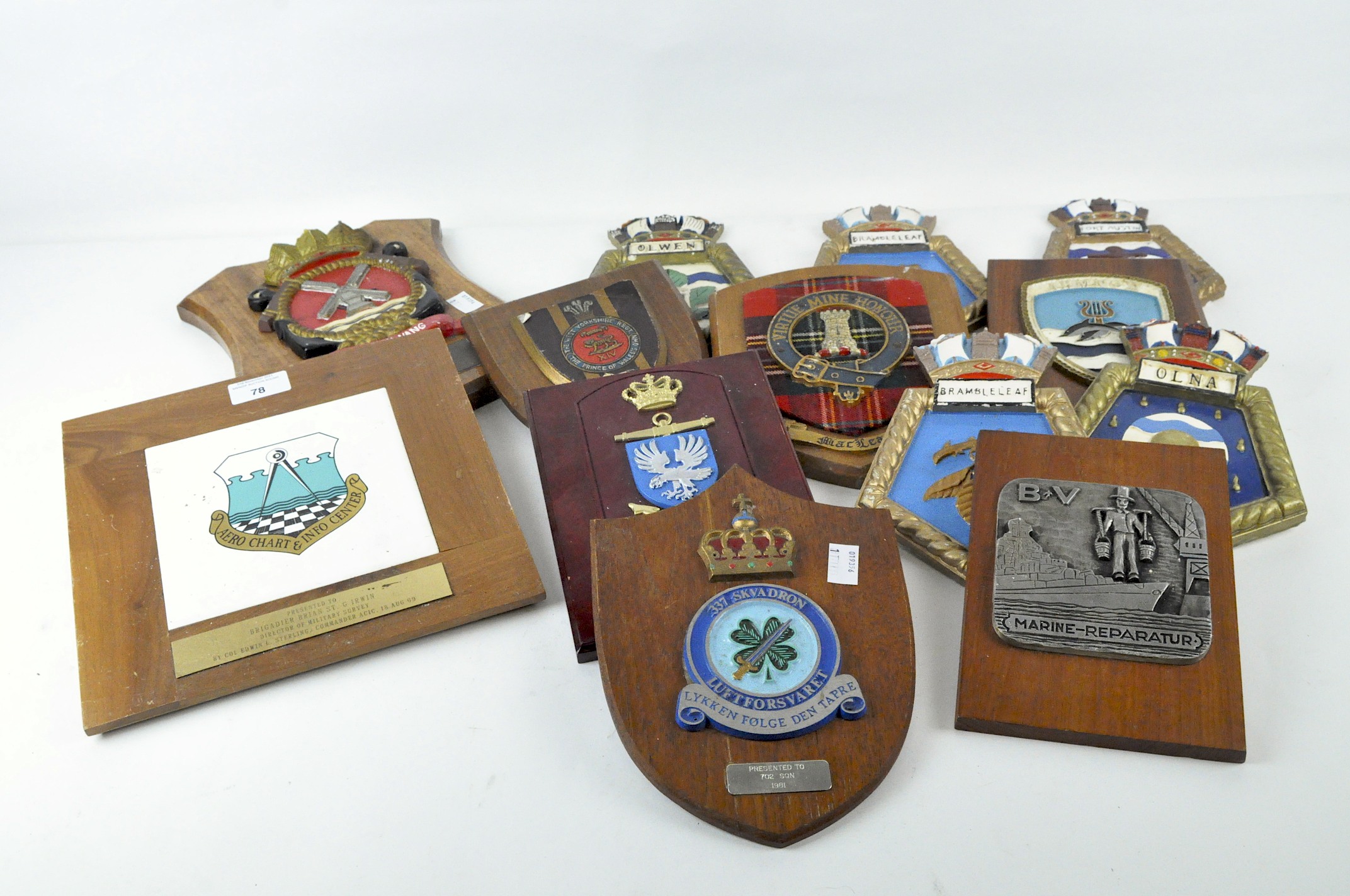 A collection of thirteen armorial wall plaques, metal and plaster in composition,