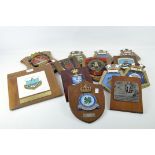A collection of thirteen armorial wall plaques, metal and plaster in composition,