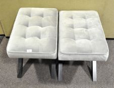 Two contemporary X-frame stools with pale grey upholstery on black supports,