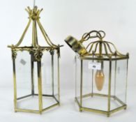 Two contemporary hanging lanterns, each with glass panels to all sides, within a brass frame,