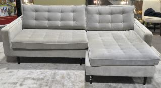 A modern corner sofa unit, raised upon tapering wooden peg feet,