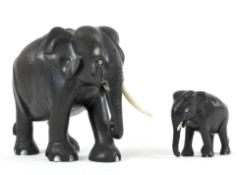 A large carved ebony and ivory inlaid elephant and baby elephant, each with ivory tusks,