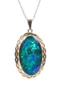 A 9ct gold marked pendant set with large black opal doublet on an unmarked yellow metal chain link