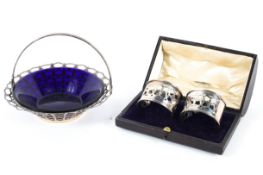 A silver basket and a pair of cased napkin rings,