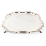 A silver salver with pie crust border, raised on hoof feet,