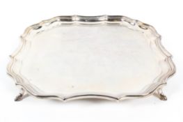 A silver salver with pie crust border, raised on hoof feet,