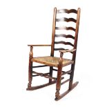 A 19th century oak ladder back rocking chair, with rush seat,
