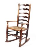 A 19th century oak ladder back rocking chair, with rush seat,