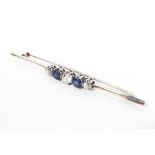 An unmarked white metal sapphire and diamond bar brooch set with two circular free cut sapphires
