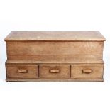 A large oak coffer, with hinged plank construction cover and three lower drawers,