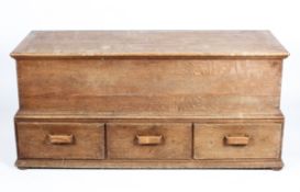 A large oak coffer, with hinged plank construction cover and three lower drawers,