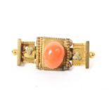 An unmarked yellow metal Etruscan style brooch set with central oval pink coral cabochon. 4.5g.