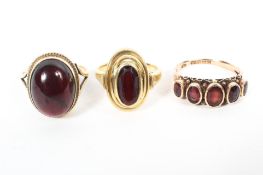 Two 9ct gold red garnet set ladies rings, together with an unmarked yellow metal example (3), 14.2g.