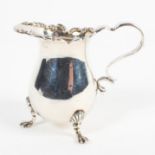 A late Victorian silver cream jug, with foliate embossed border, raised upon three lion paw feet,