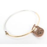 A 9ct white and yellow gold bangle bracelet together with a 9ct rose gold locket. 8.2g.