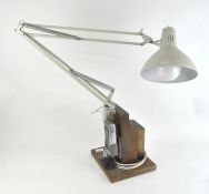 A vintage anglepoise style lamp, mounted on wooden base,