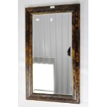 A stained wooden bevelled edged wall mirror, of rectangular form,