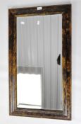 A stained wooden bevelled edged wall mirror, of rectangular form,
