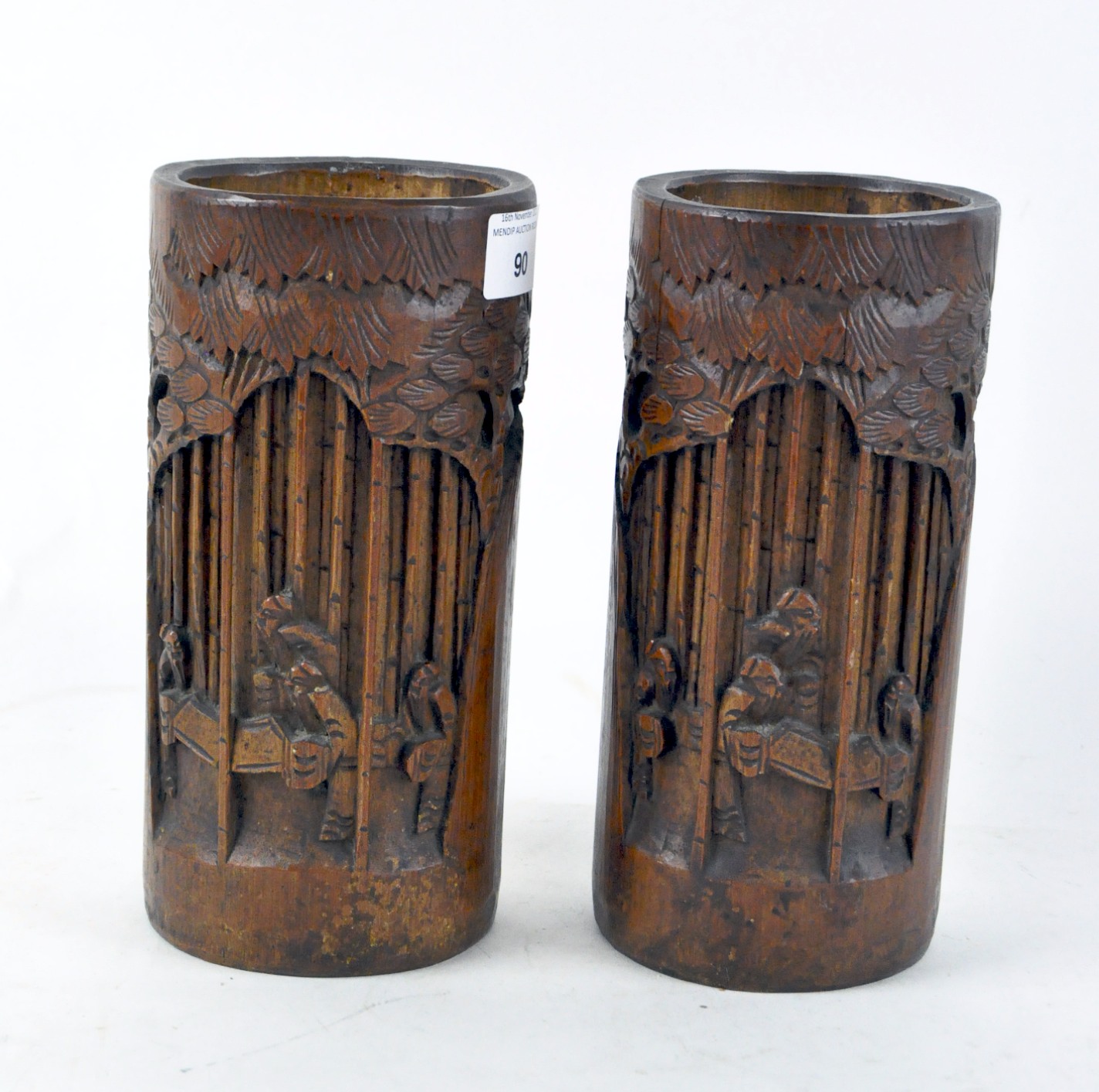 A pair of Chinese bamboo brush pots, carved with scenes of scholars amongst trees,