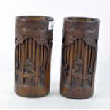 A pair of Chinese bamboo brush pots, carved with scenes of scholars amongst trees,