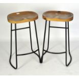 A pair of modern bar stools with wooden seats and metal frames,