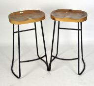 A pair of modern bar stools with wooden seats and metal frames,
