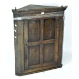 A 19th century oak corner cabinet, opening to reveal 2 shelves,