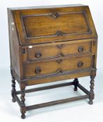 An early 20th century oak bureau, the drop front over two long drawers,