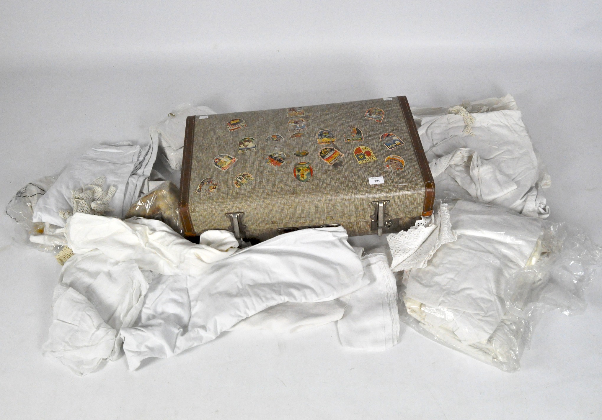 A vintage travelling case containing a collection of linen and fur gloves