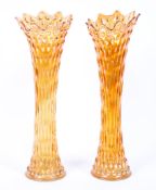 A pair of large orange carnival glass vases, with textured exteriors and fluted rims,