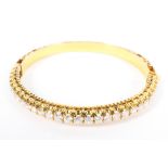 An unmarked yellow metal and diamond bangle half set with single line of 28 diamonds. 25g.