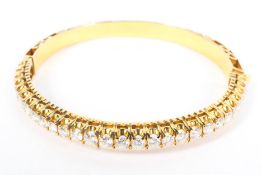 An unmarked yellow metal and diamond bangle half set with single line of 28 diamonds. 25g.