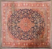 A large Persian silk/wool rug red ground with central floral panel and three floral; borders.