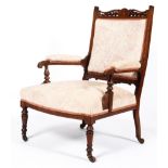 A Victorian rosewood upholstered armchair in floral fabric on turned front legs on original castors.