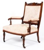 A Victorian rosewood upholstered armchair in floral fabric on turned front legs on original castors.